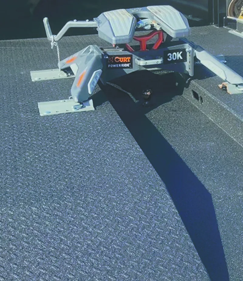 The coated bed of a trailer, dark grey with a fine anti-slip texture, under a fifth-wheel hitch.