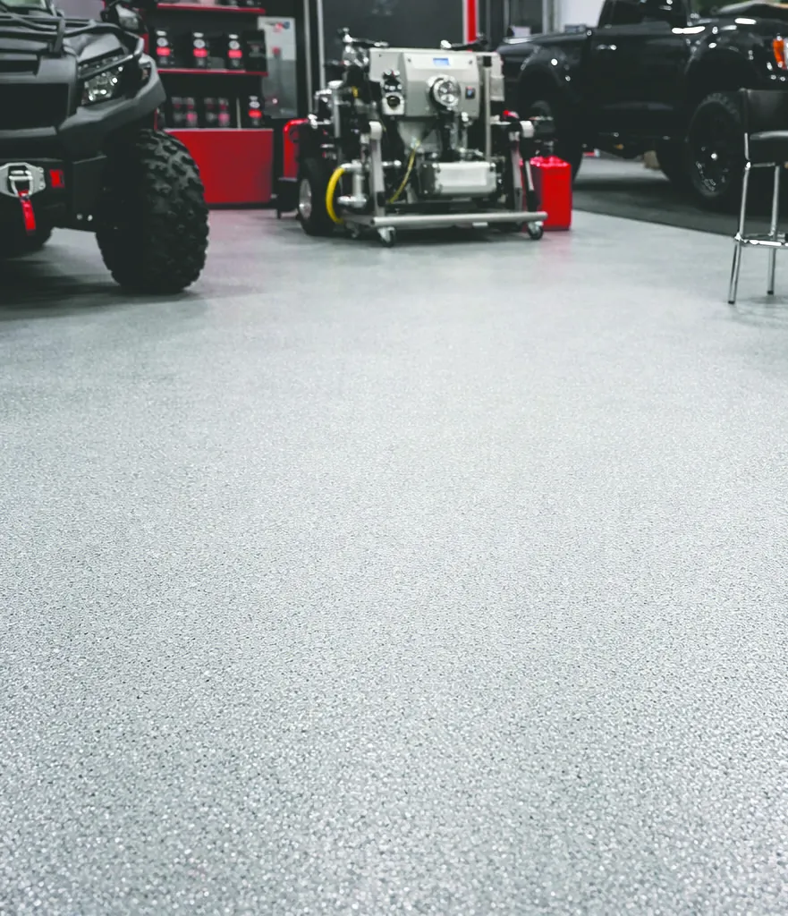 A grey speckled BAS Flexcoat floor in a workshop, with a quad bike and a spray rig parked on it.