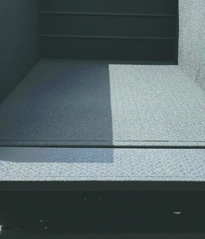 The cured BAS Flexcoat floor at MOWI meeting a step and a wall, one continuous membrane across both.