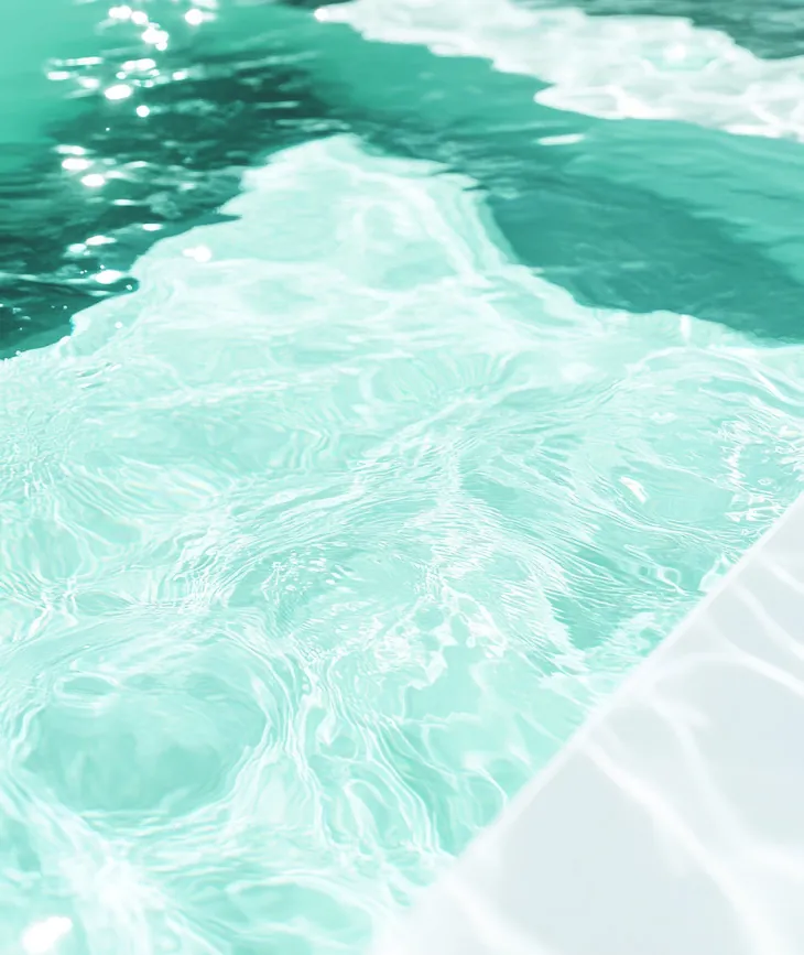 Sunlight moving across the water of a pool with a pale coated edge.