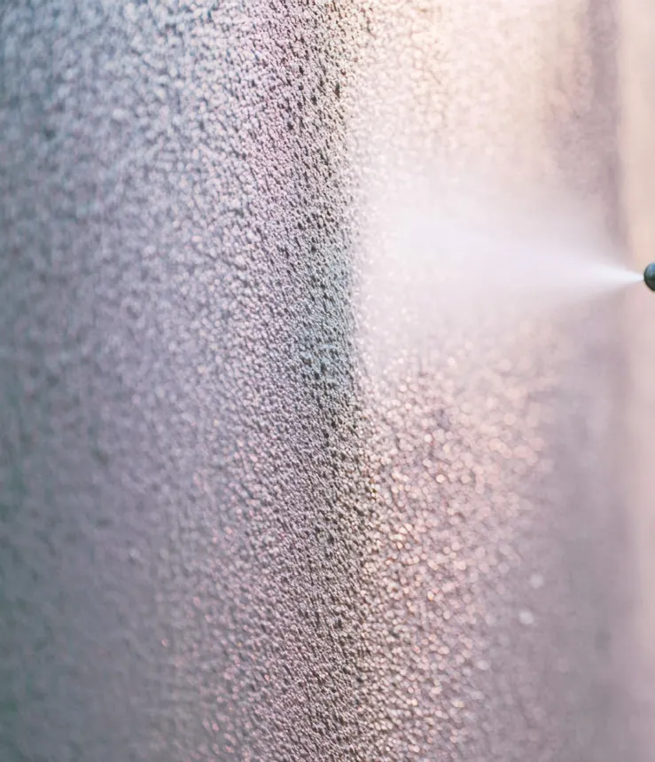 A spray gun laying BAS Flexcoat onto a wall, the wet membrane fanning out from the nozzle.