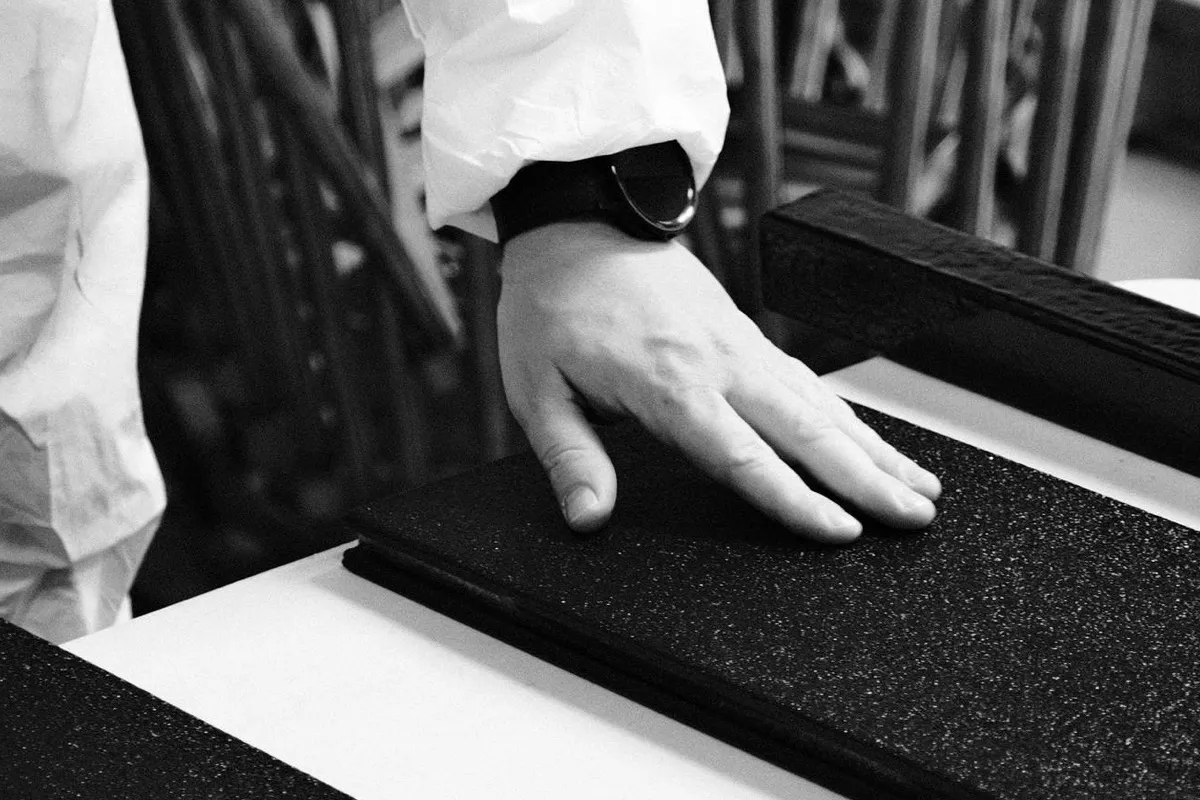 A hand checking the coated surface of a BAS Board on the workshop table.