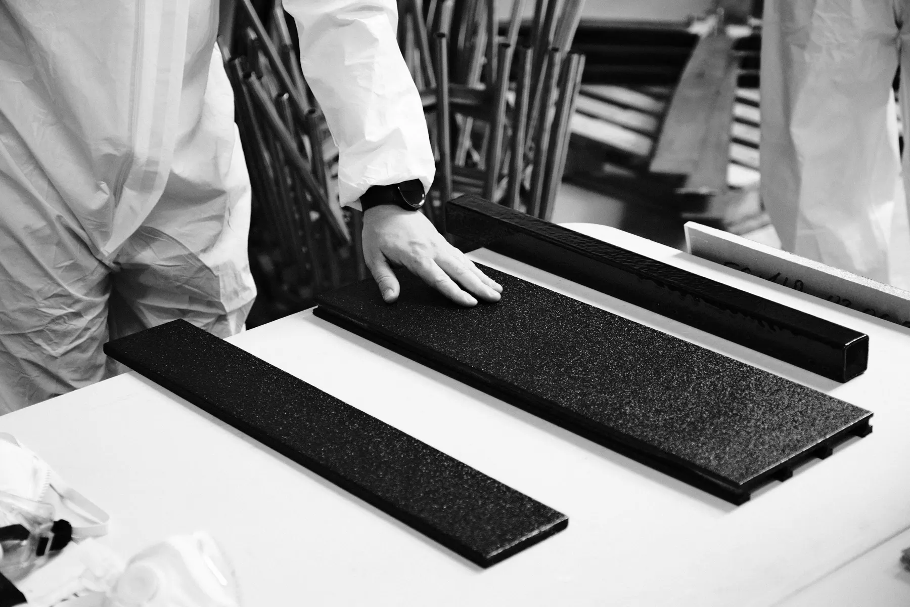 A hand resting on a textured black basalt board on a workshop table.